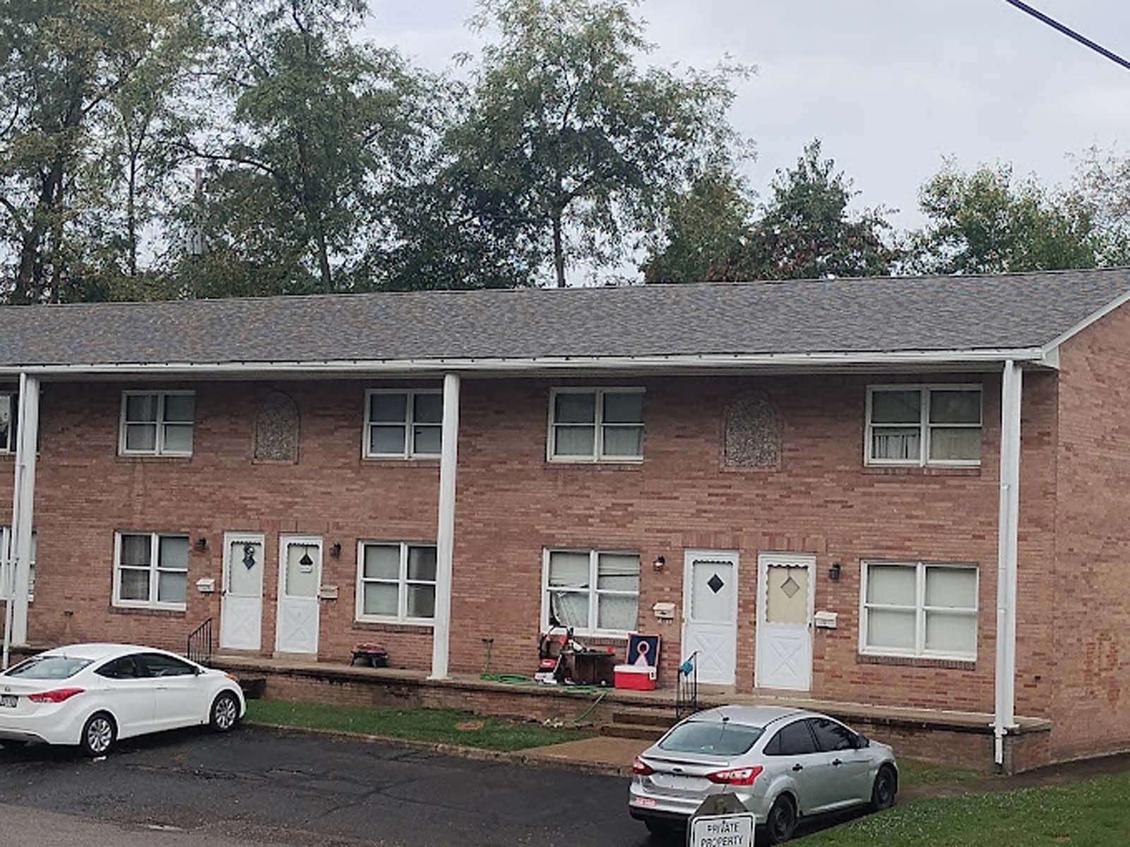 A brick apartment building with cars parked in front of it.