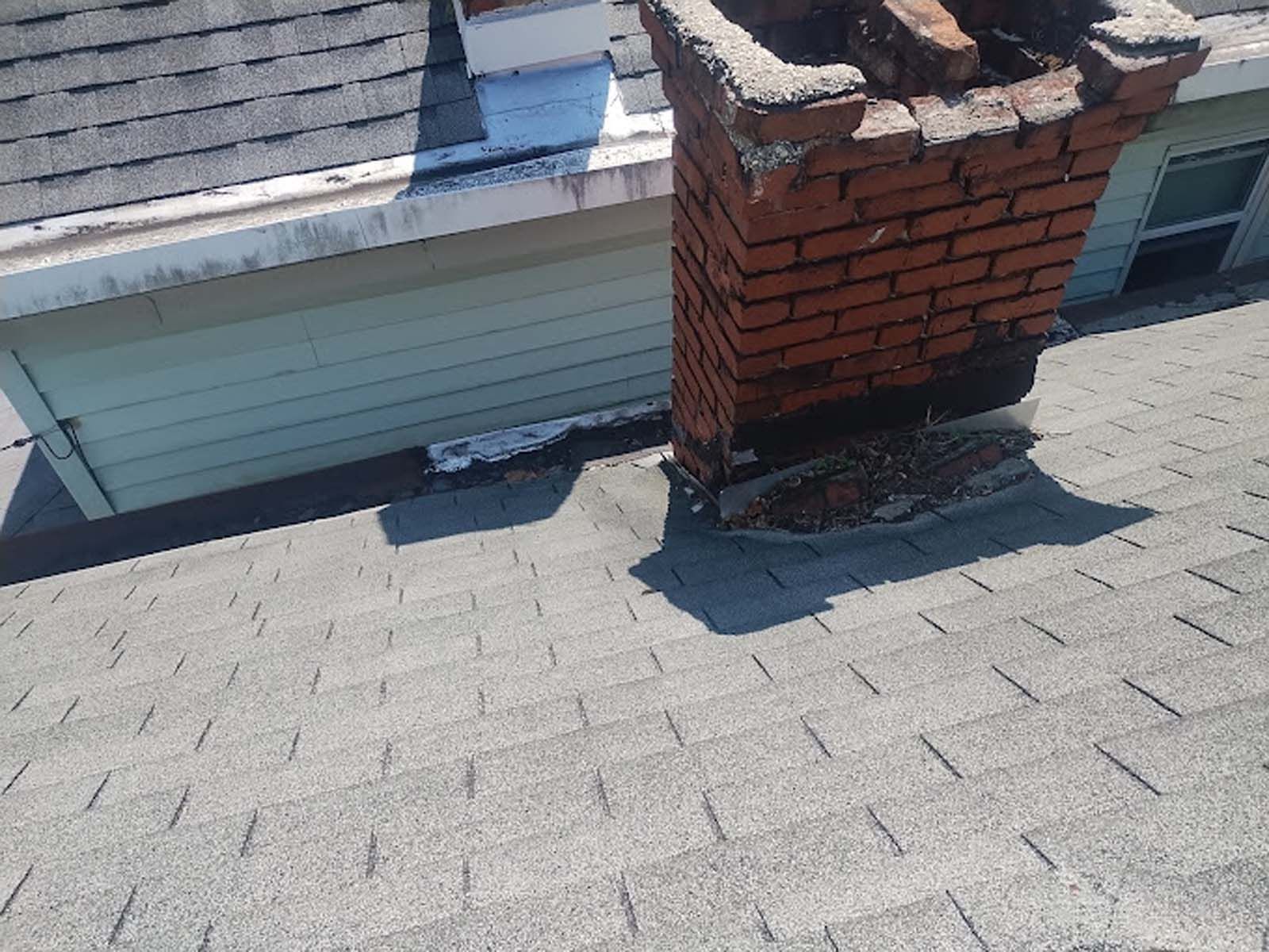 A brick chimney is sitting on top of a roof.