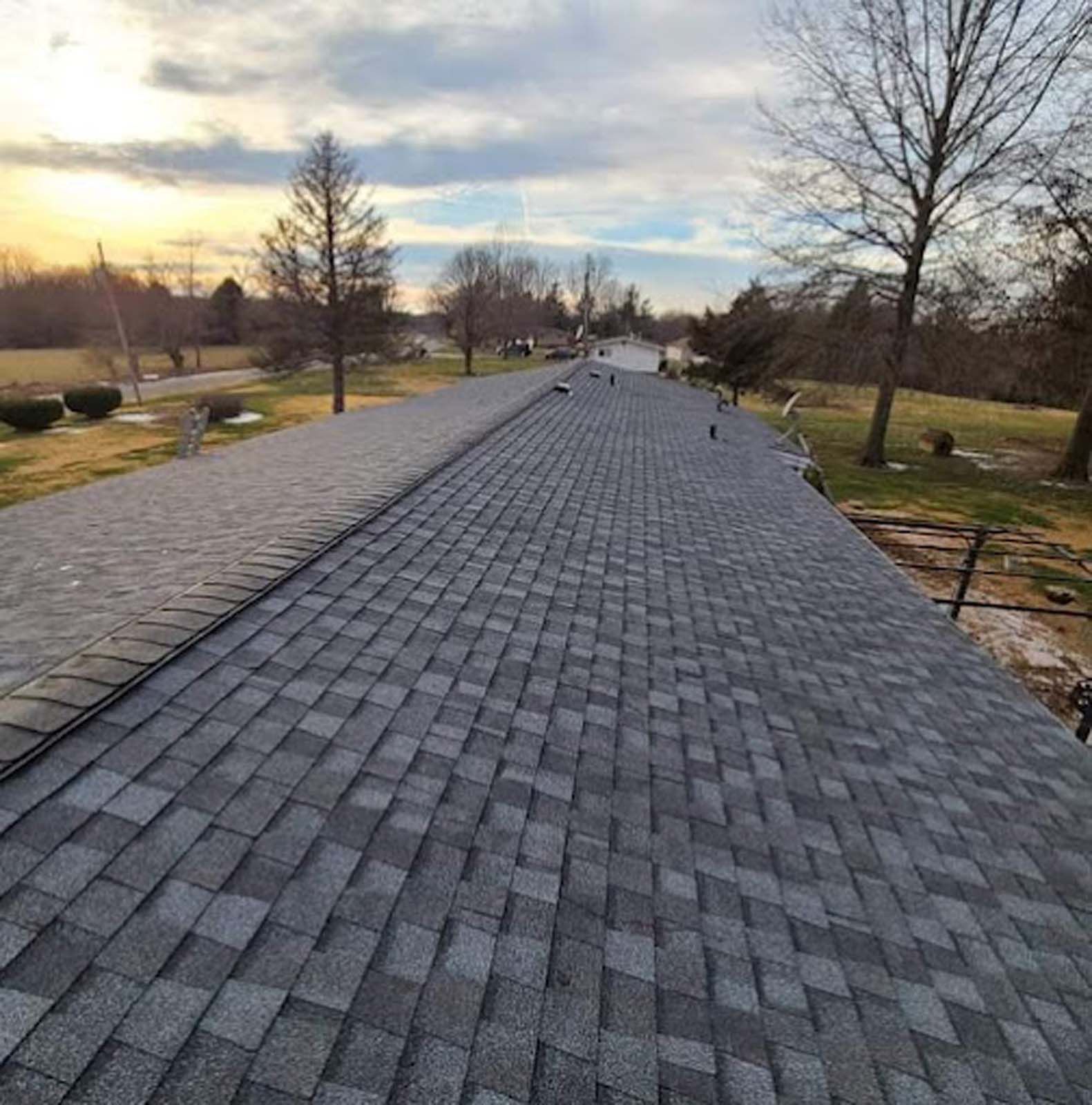 A roof with a lot of shingles on it and trees in the background.