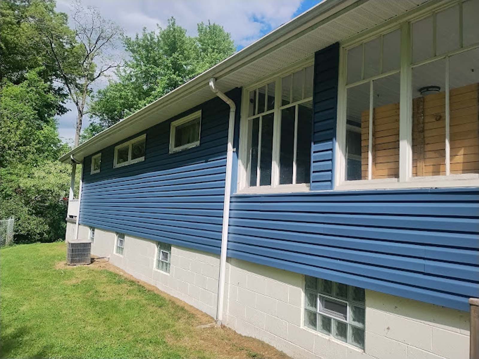The side of a house with blue siding and white windows.