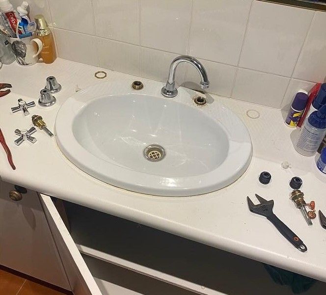 Bathroom Sink With Dismantled Faucet Parts on the Counter — C’s Plumbing & Gas Gold Coast in Yatala, QLD