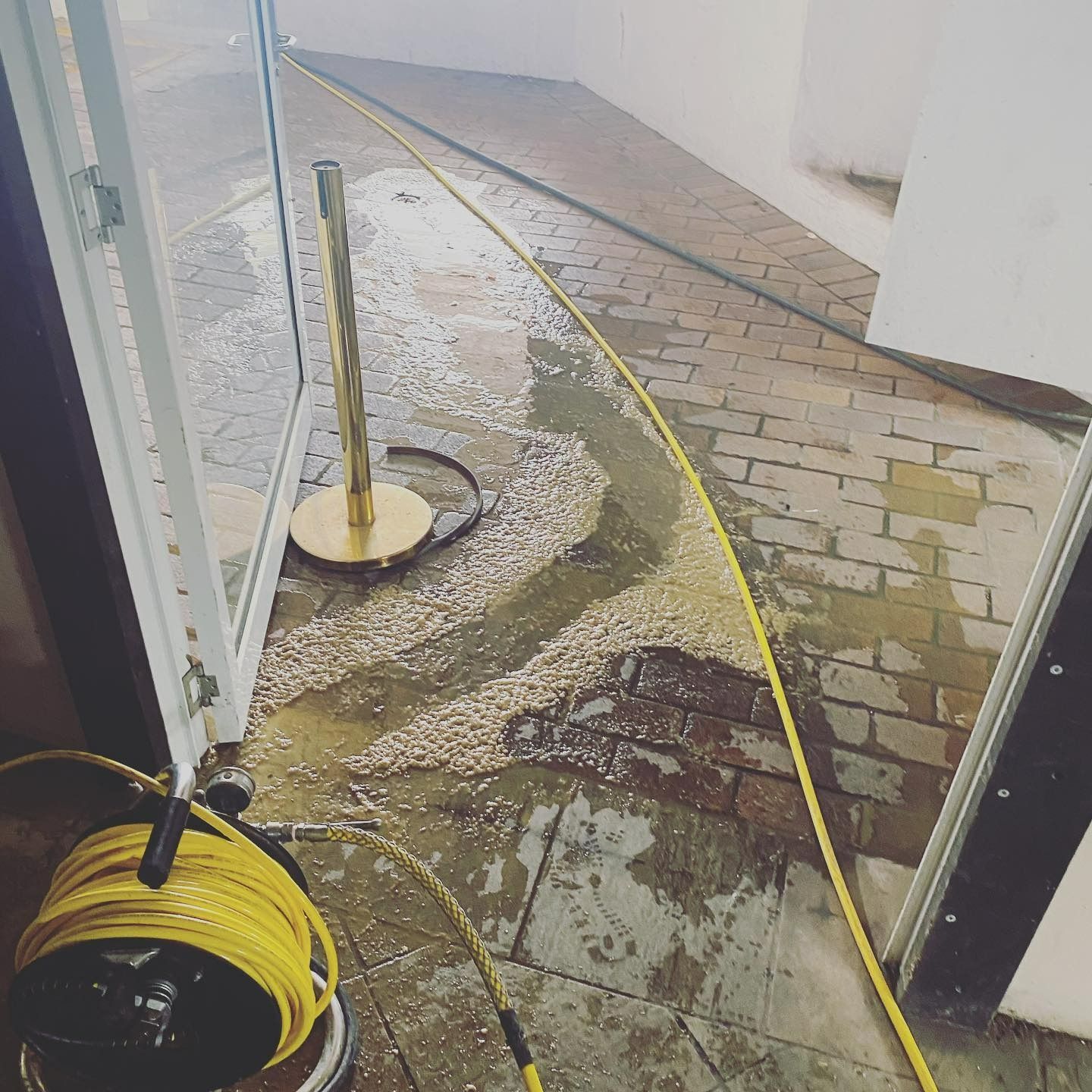 Flooded Entryway With Yellow Hose and Water — C’s Plumbing & Gas Gold Coast in Yatala, QLD