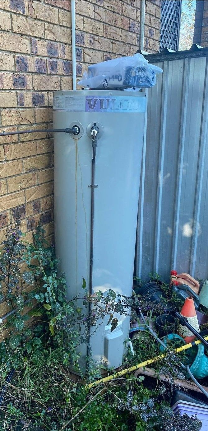 Outdoor Water Heater Next to a Brick Wall and a Fence — C’s Plumbing & Gas Gold Coast in Yatala, QLD