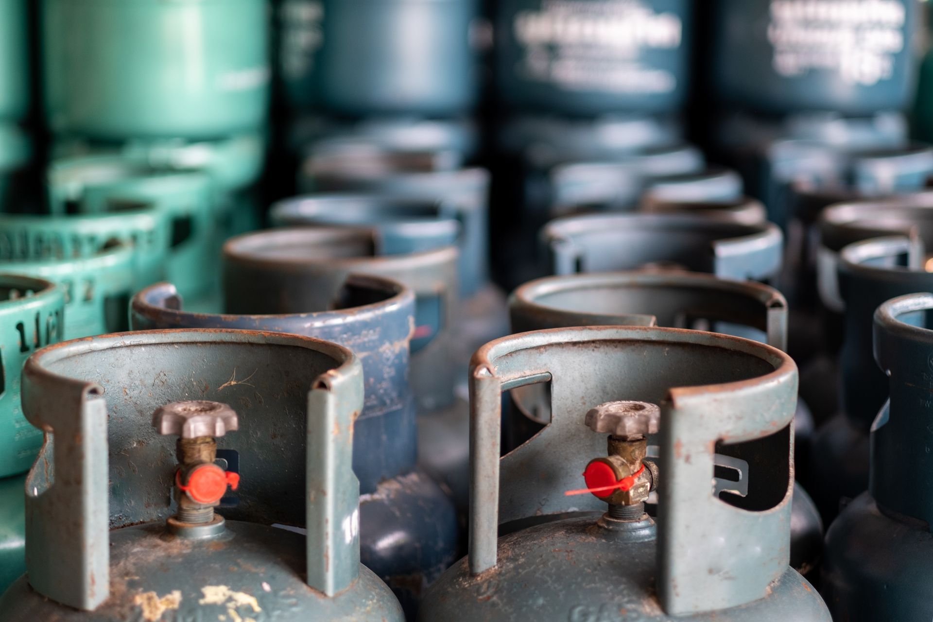 Rows of blue and teal propane tanks with valves and gauges visible.