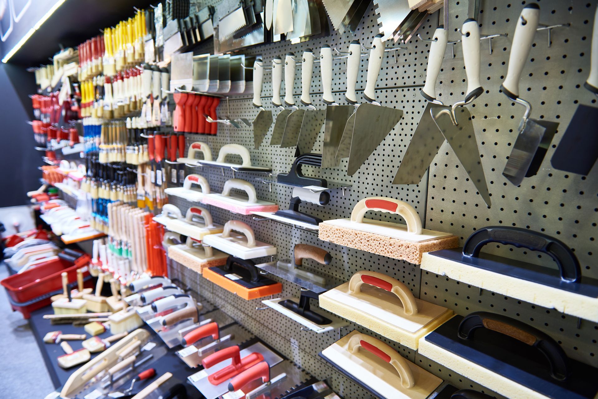 Tools for construction, including brushes, trowels, and floats, on display in a store.
