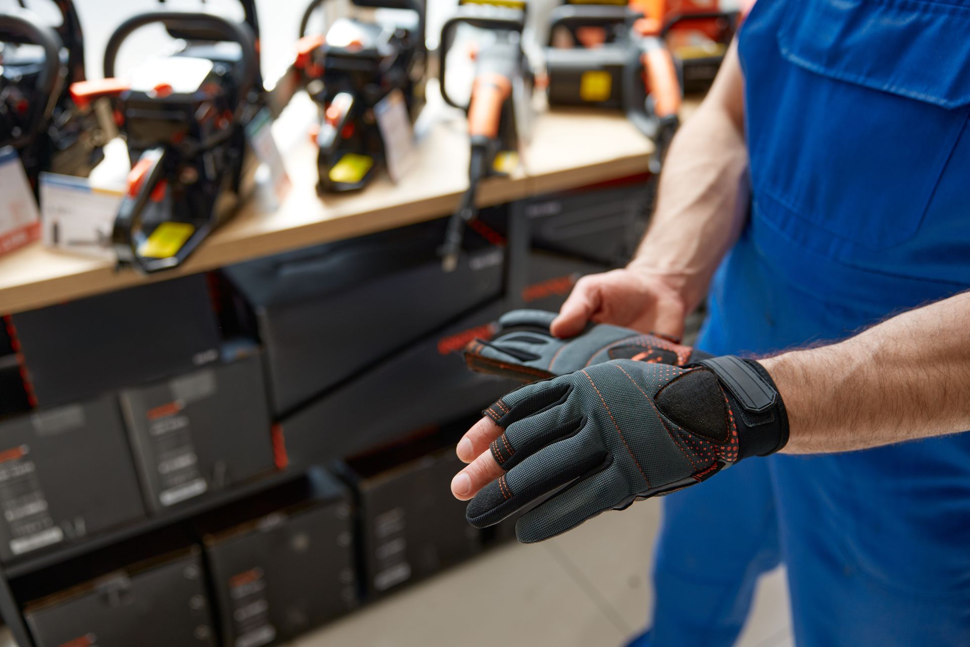 Person wearing black work gloves in a store with chainsaws on display.
