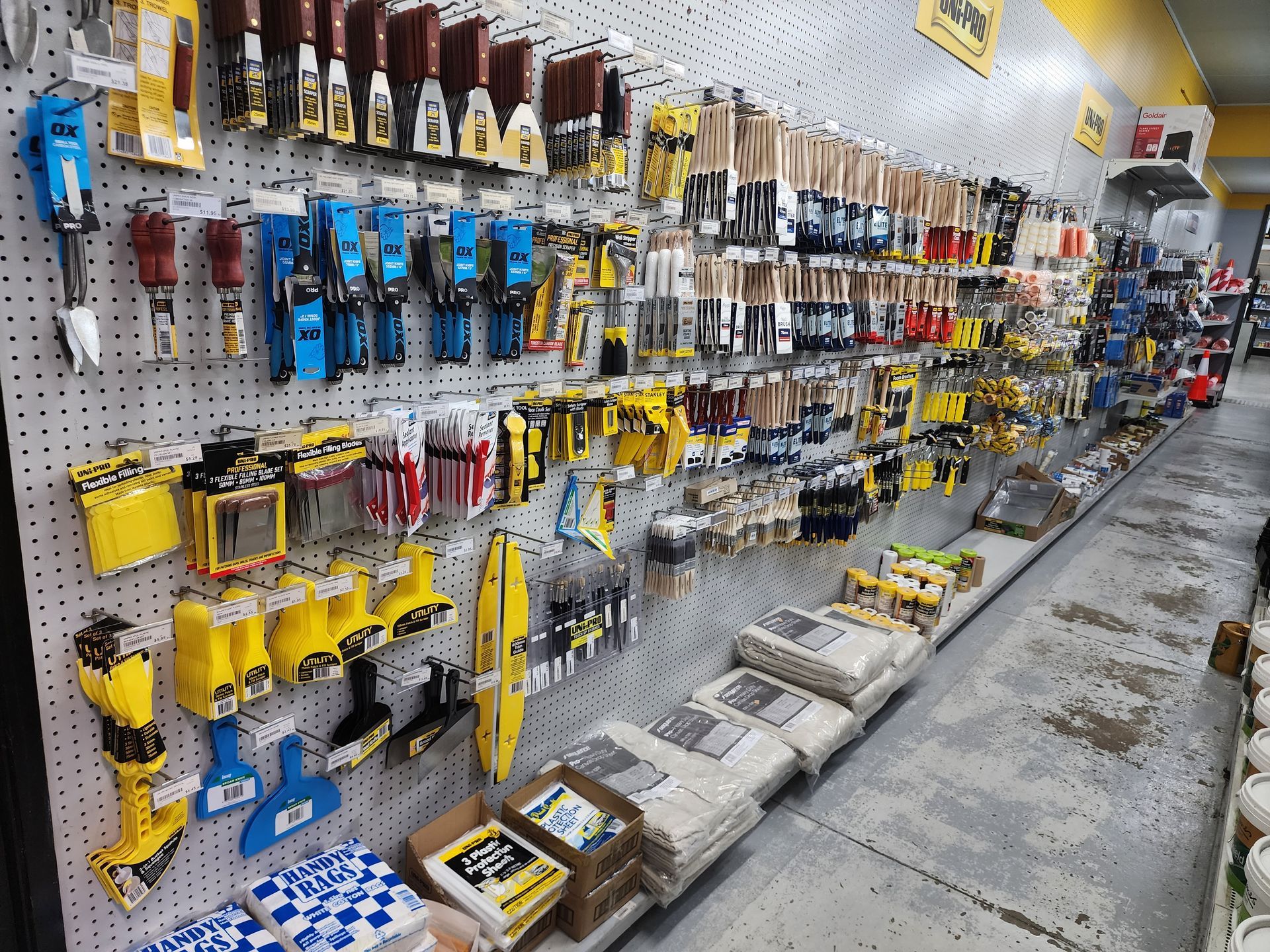 Tools and paintbrushes displayed on pegboards in a hardware store.