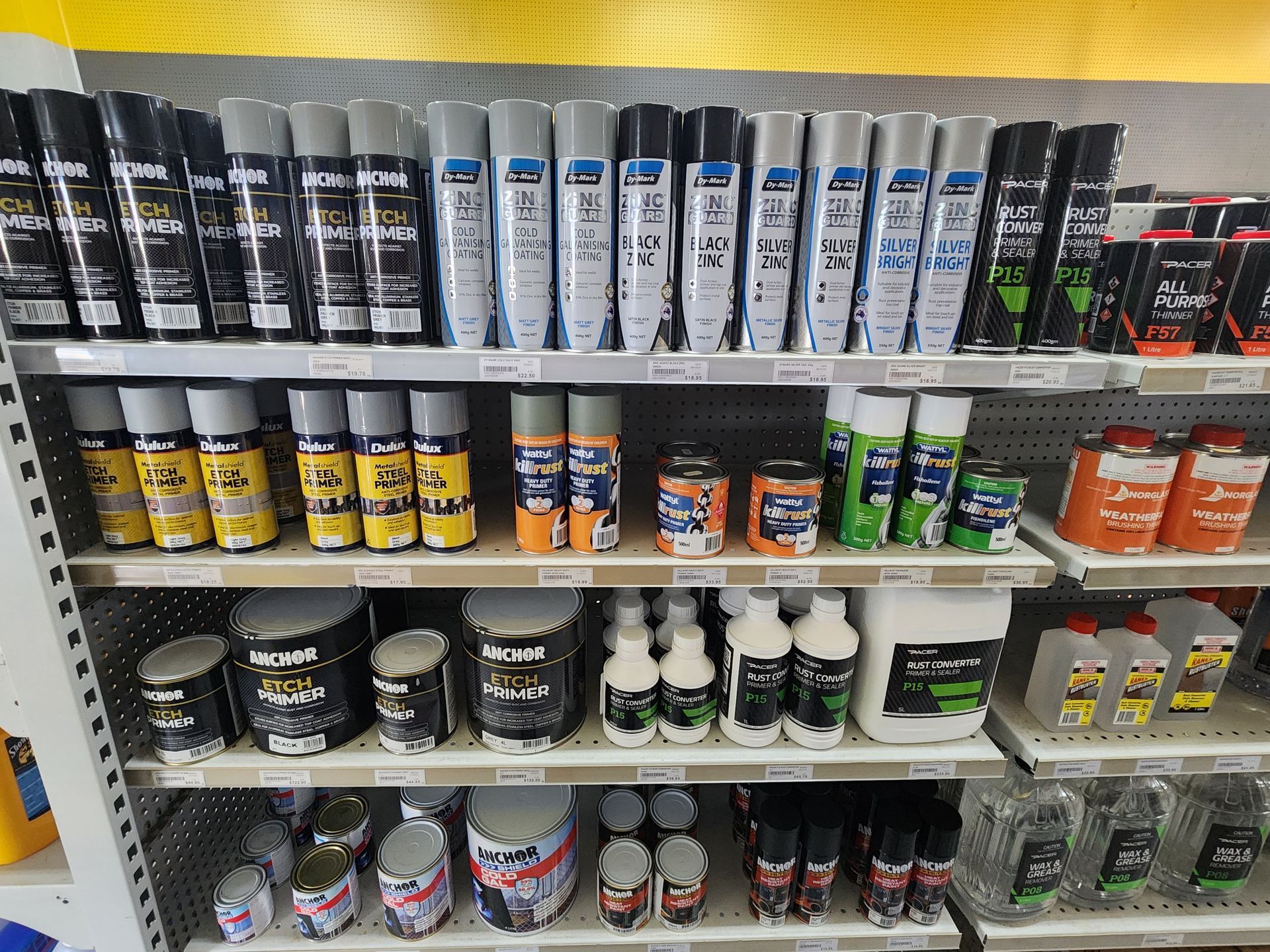 Shelves stocked with various aerosol cans and bottles of automotive paint and cleaners in a store.