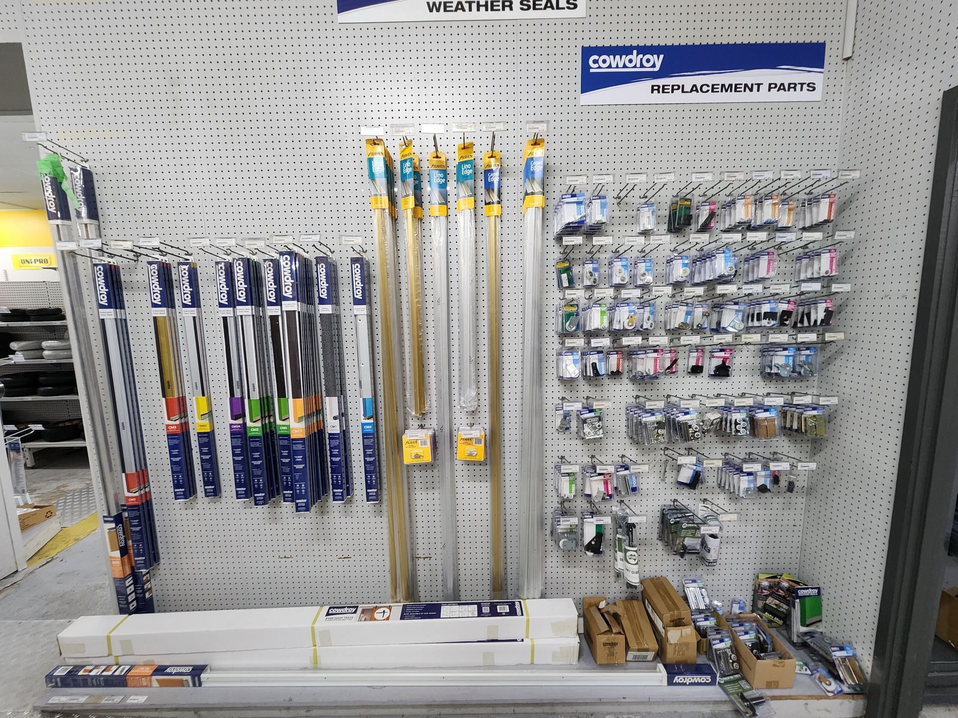 Display of auto parts in a store, including windshield wipers, accessories, and packaged components on a pegboard wall.