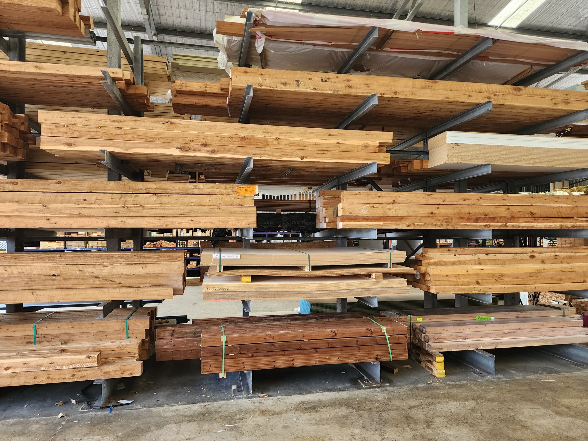 Wooden planks stacked on shelves in a lumberyard, showcasing various textures and colors.