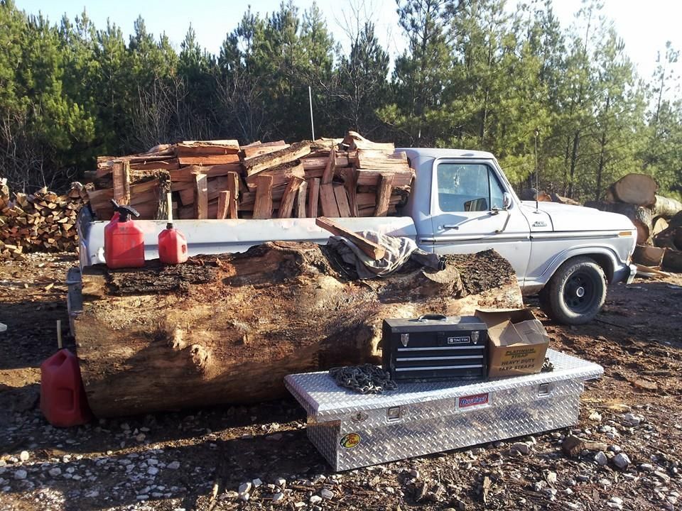 A white truck with a large log in the back