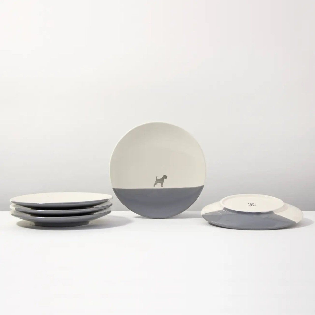 Bord met grijze onderkant, crèmekleurige bovenkant en silhouet van een hond.
