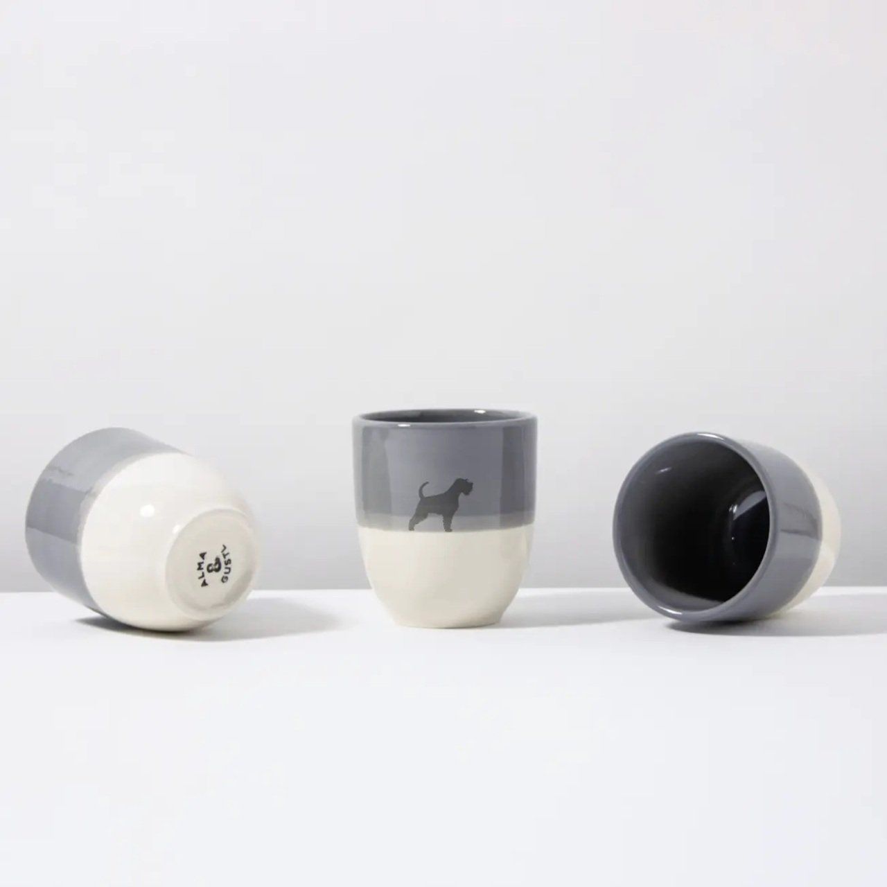 Grijze en crèmekleurige keramische beker met een hondensilhouet.