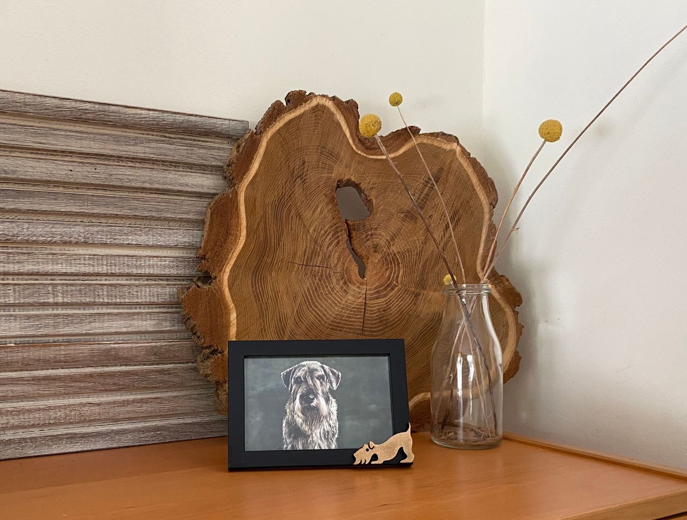 Een afbeelding van een hond die op een houten tafel zit naast een vaas.