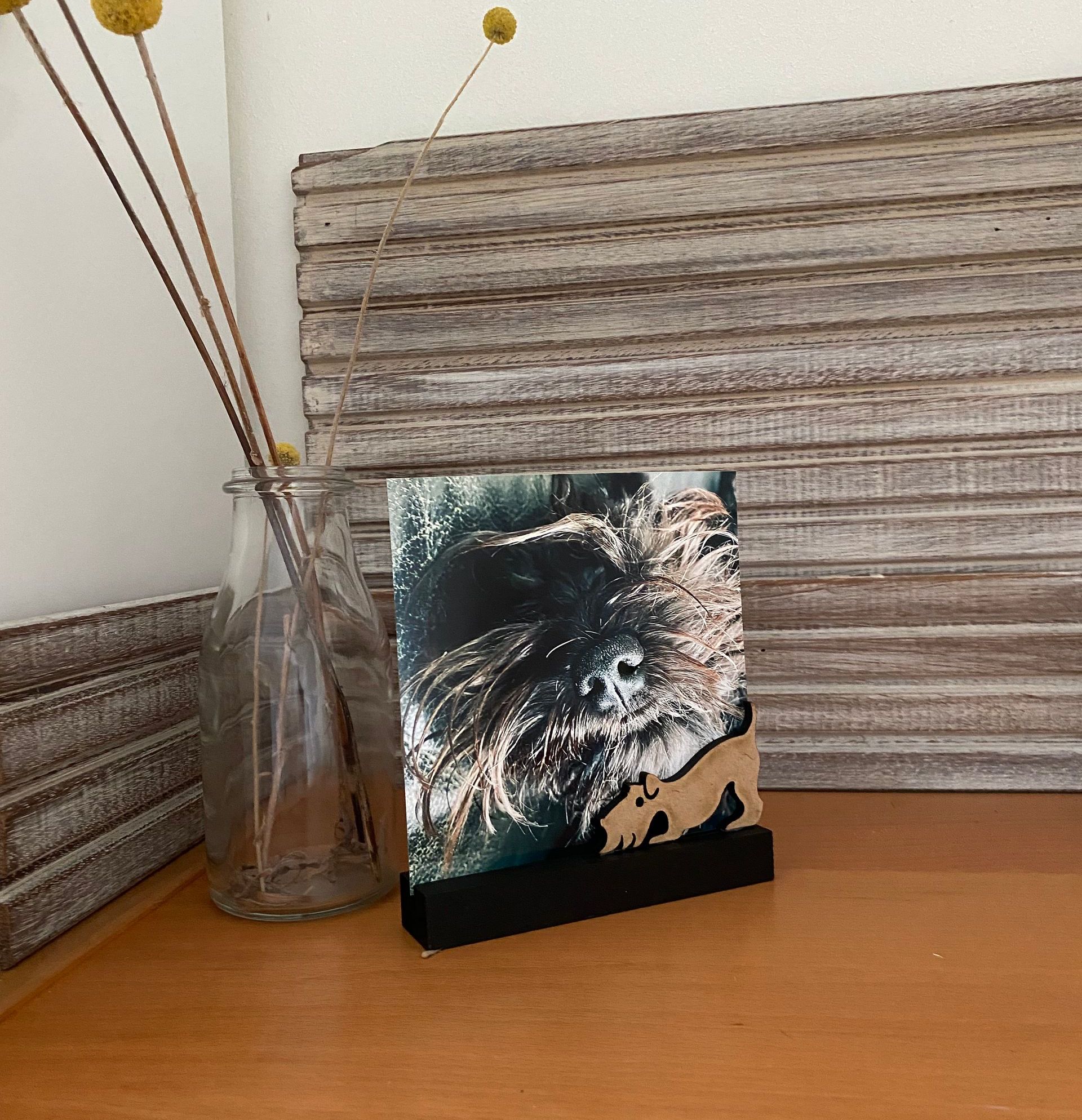 Zwart metalen hondenbeeldje op een rechthoekige voet; houten achtergrond.