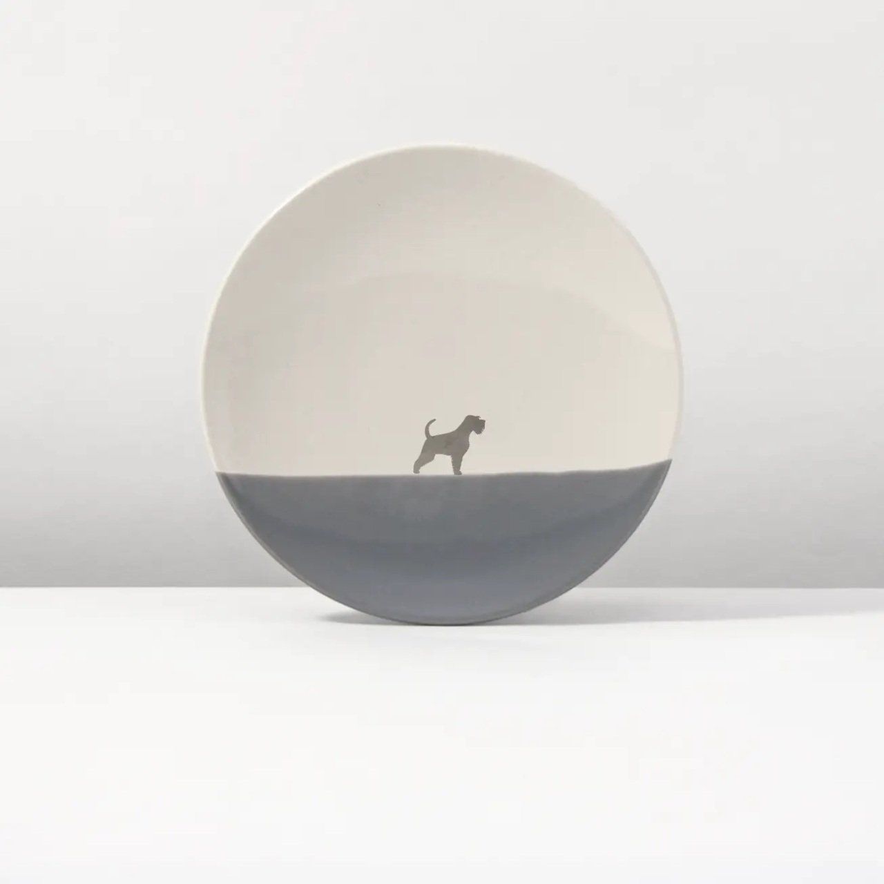Een wit en grijs bord met daarop een silhouet van een hond