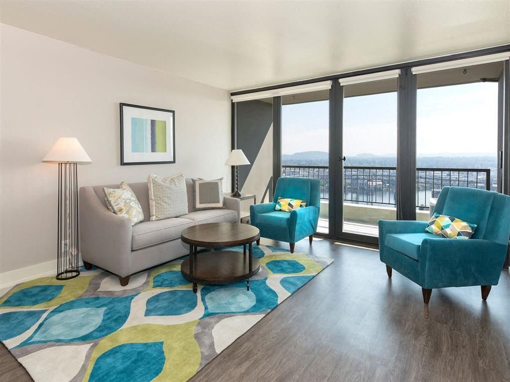 Living room with a grey sofa, two teal chairs, a coffee table, and large doors to a balcony.