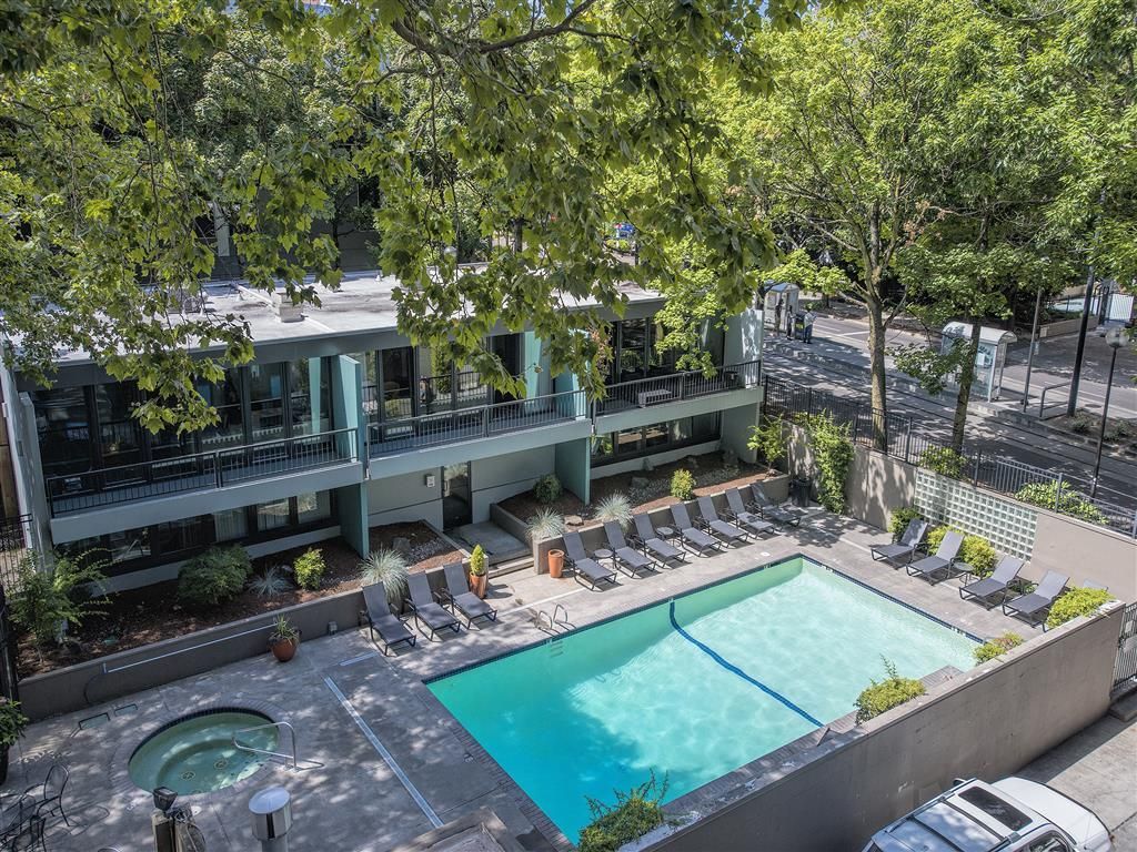Outdoor apartment pool with a circular hot tub and lounge chairs.