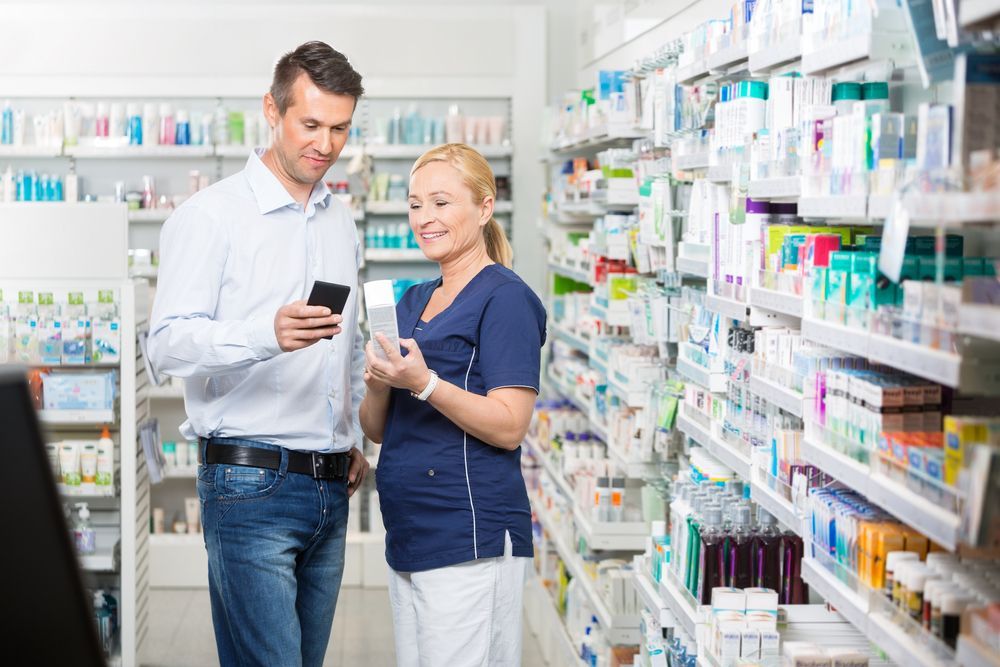 A Man and a Woman Are Looking at a Cell Phone in a Pharmacy — Bluewater Pharmacy in Yabulu, QLD