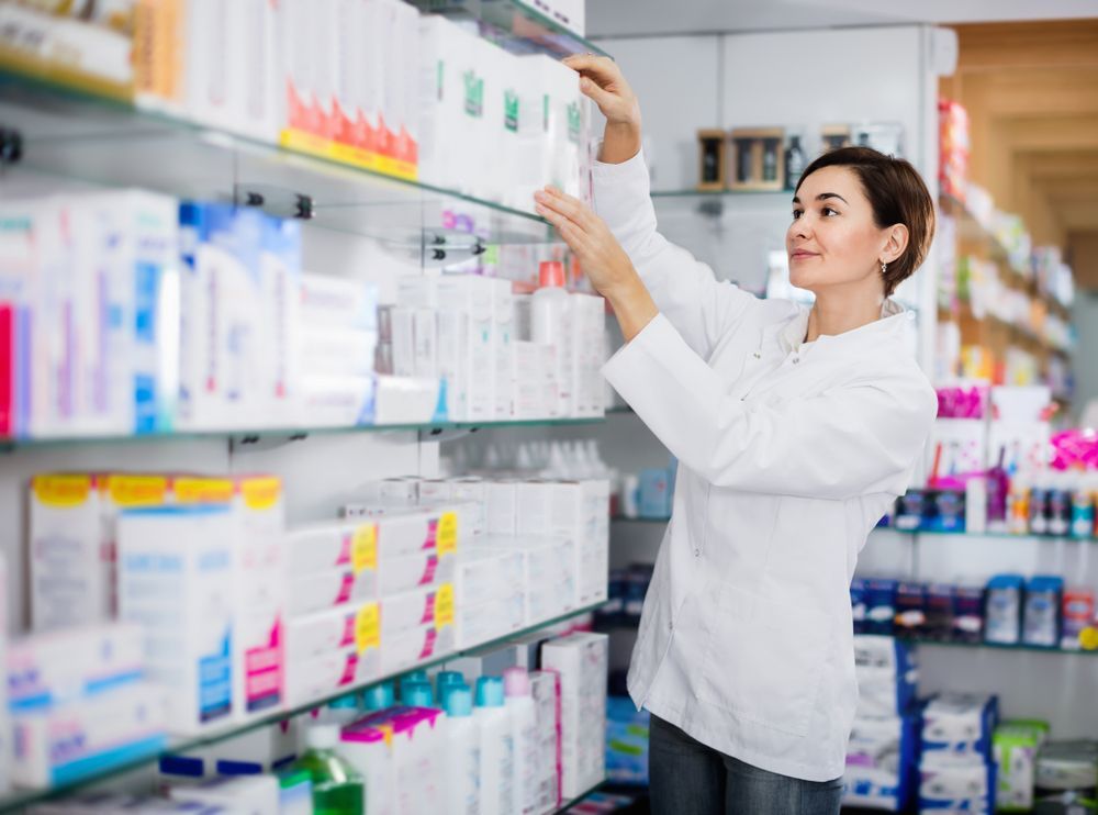 A Female Pharmacist is Reaching for a Bottle in a Pharmacy — Bluewater Pharmacy in Balgal, QLD