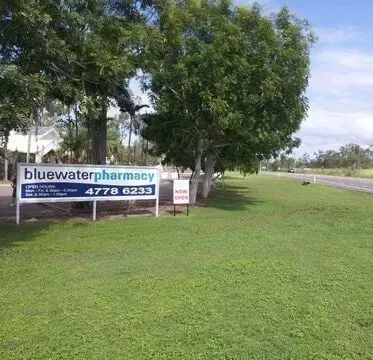 A Blue Water Pharmacy Sign is in the Grass Near a Road — Bluewater Pharmacy in Yabulu, QLD