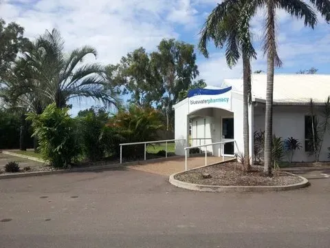 A White Building With Palm Trees in Front of It — Bluewater Pharmacy in Yabulu, QLD