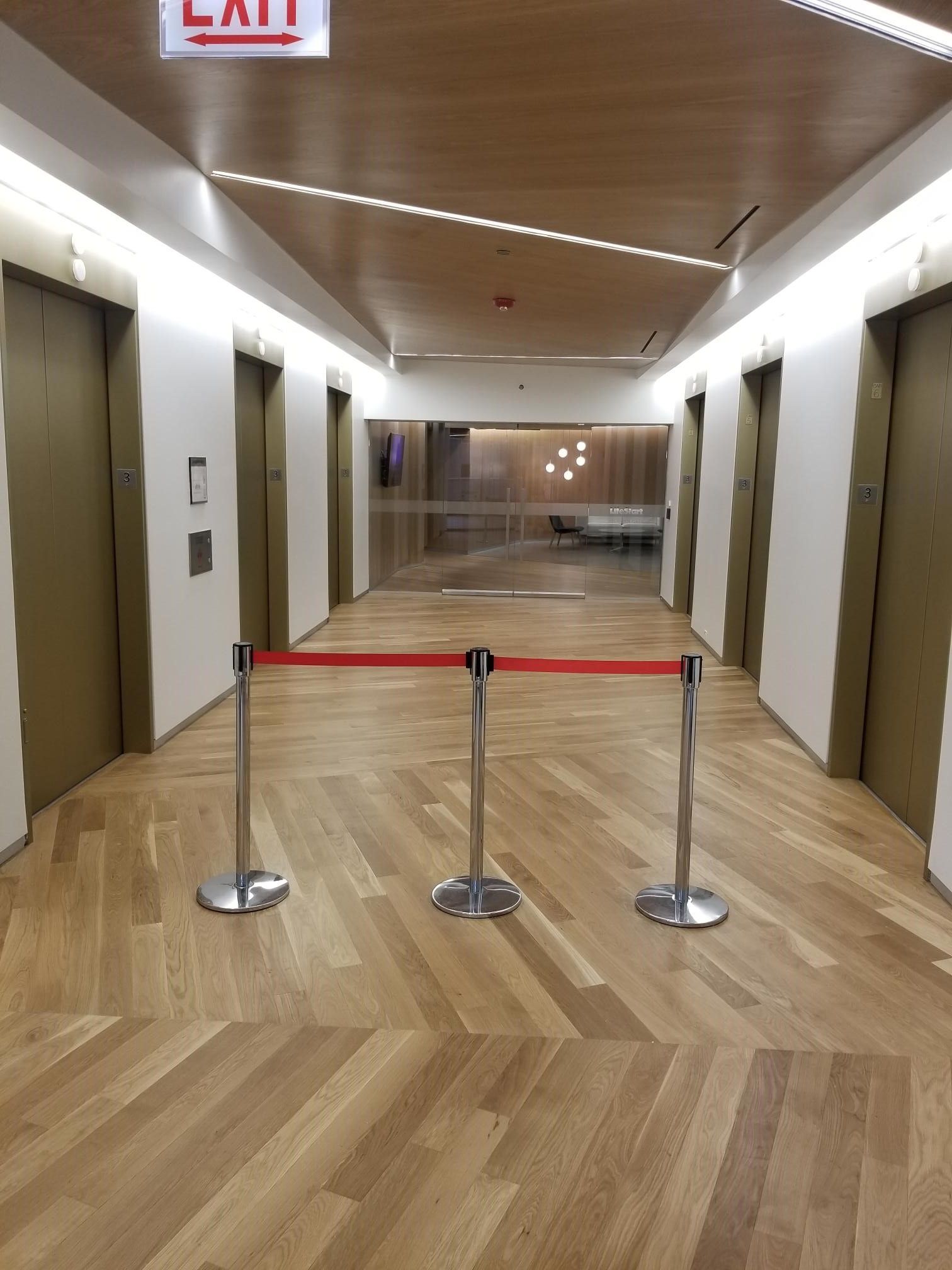 A long hallway with a red exit sign above it