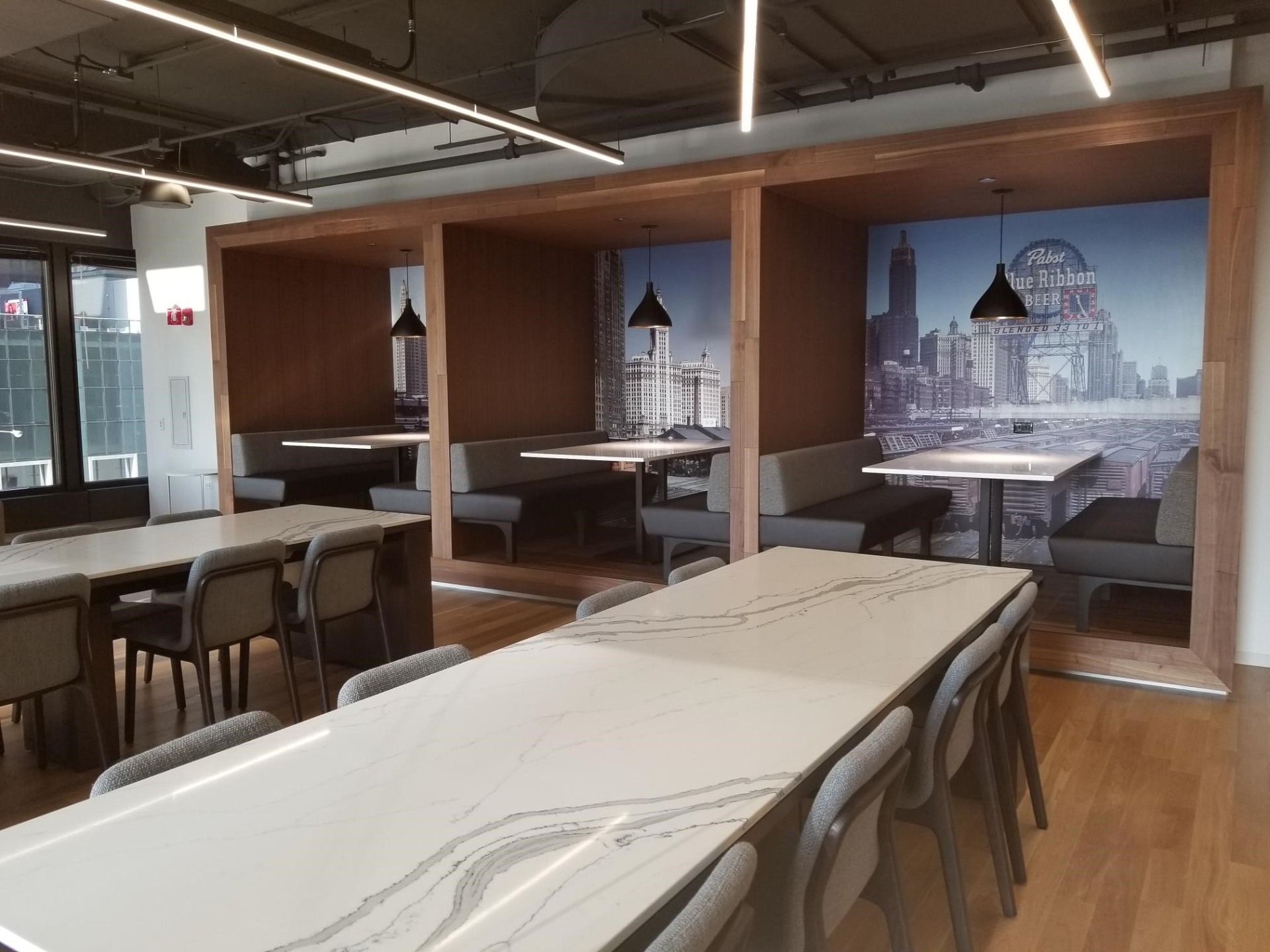 A dining room with tables and chairs and a picture of a city on the wall.