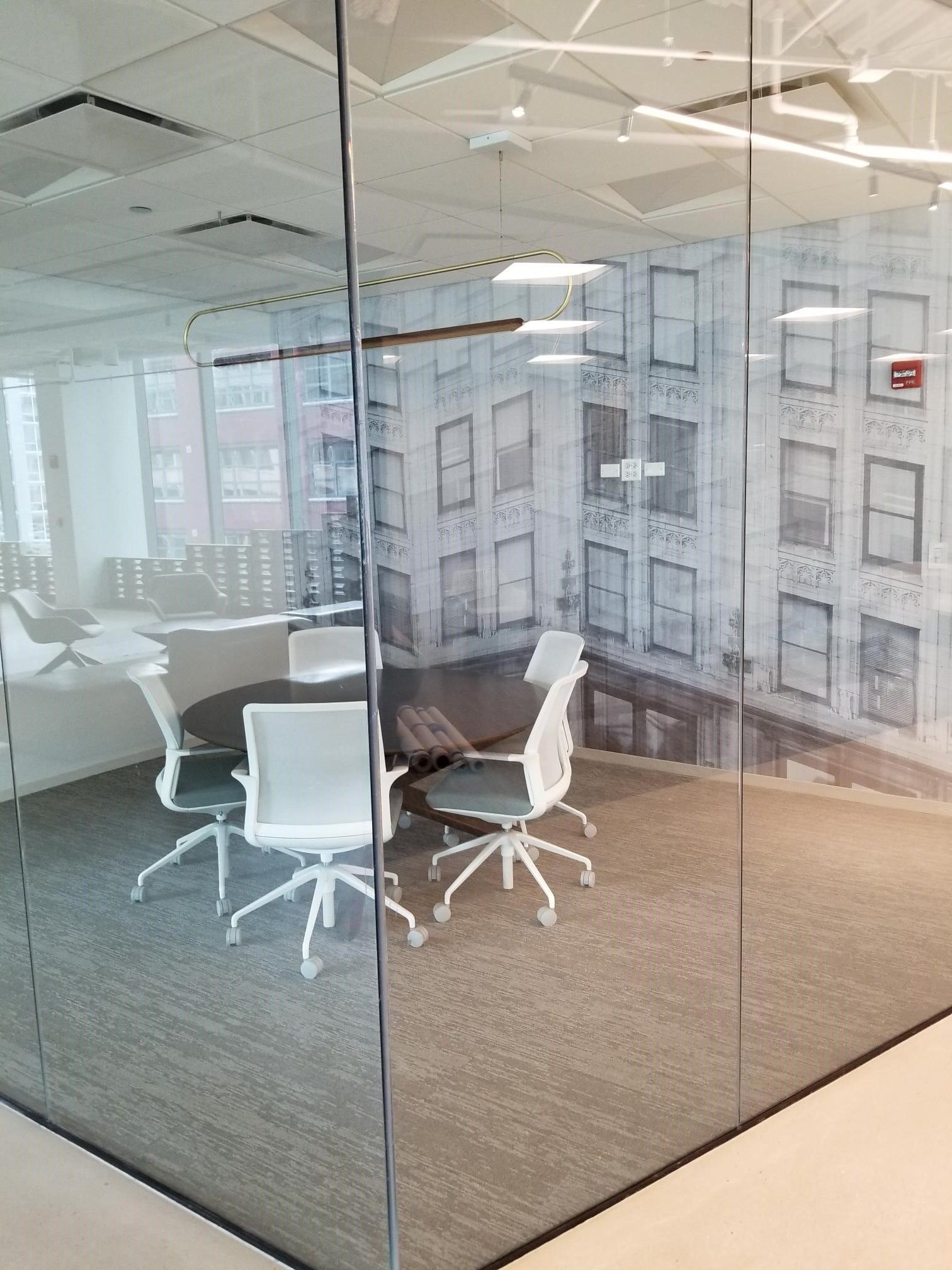 A conference room with a table and chairs behind a glass wall.