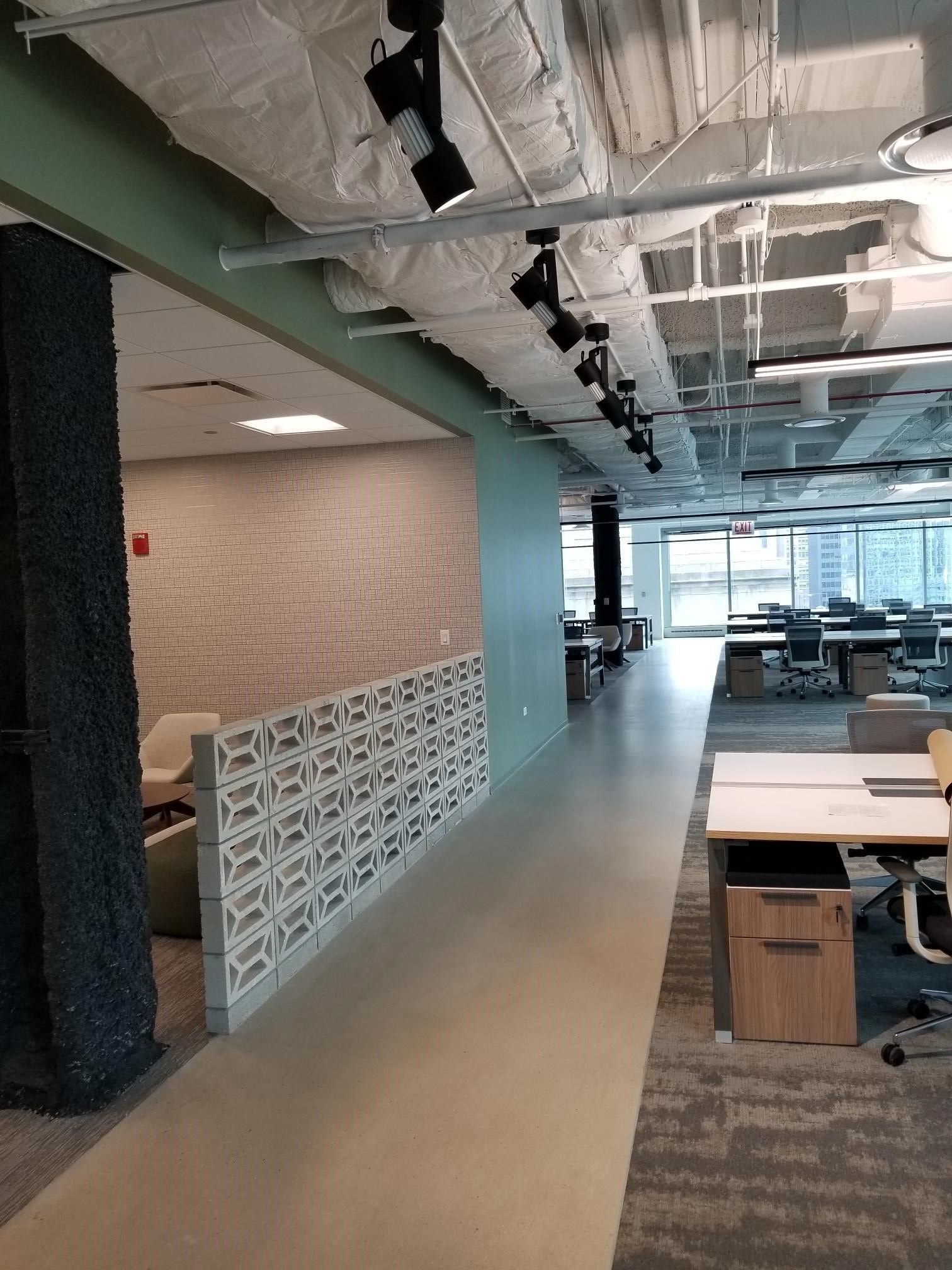 A long hallway in an office building with tables and chairs.
