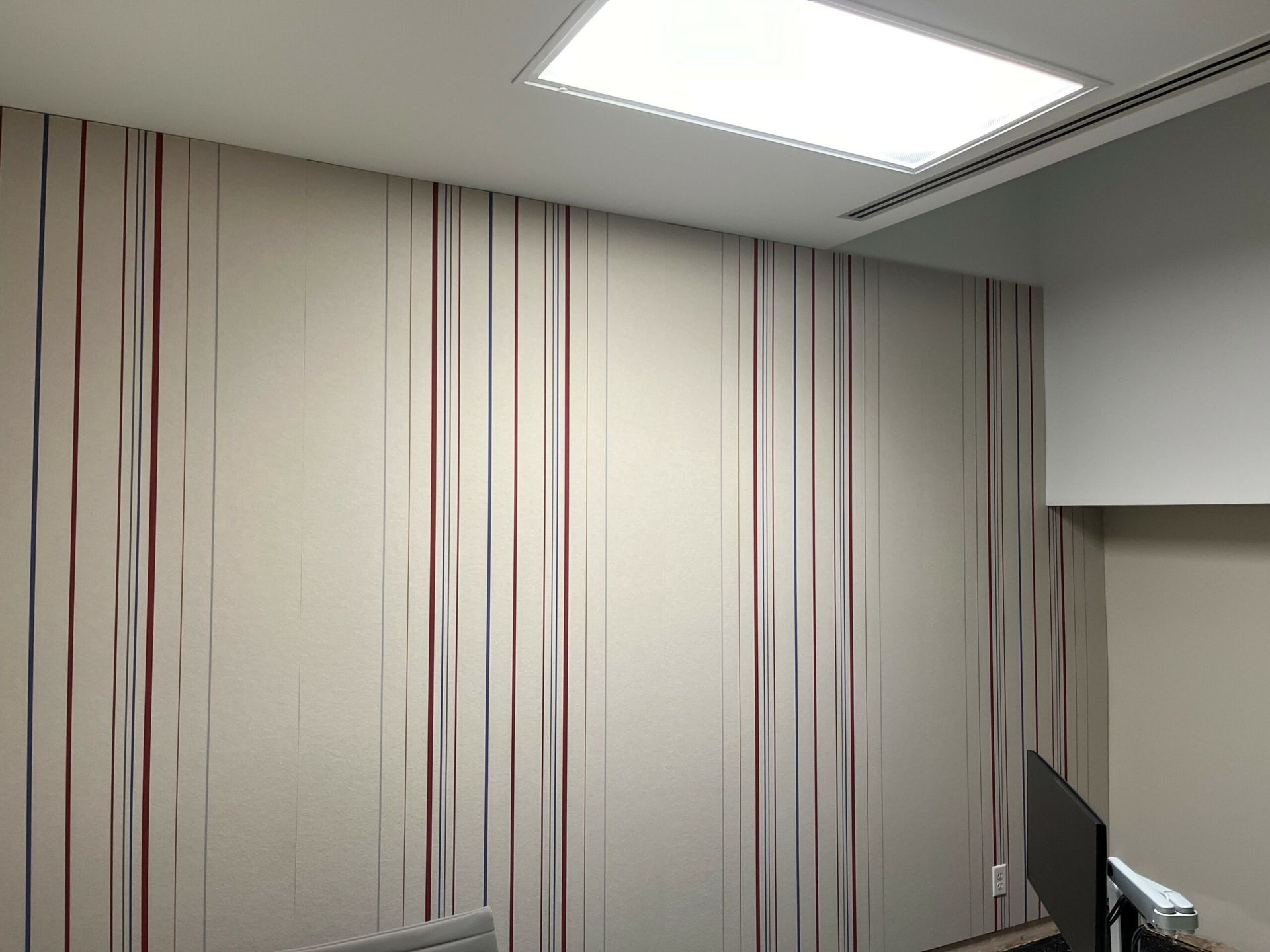 A room with a striped wall and a ceiling light.