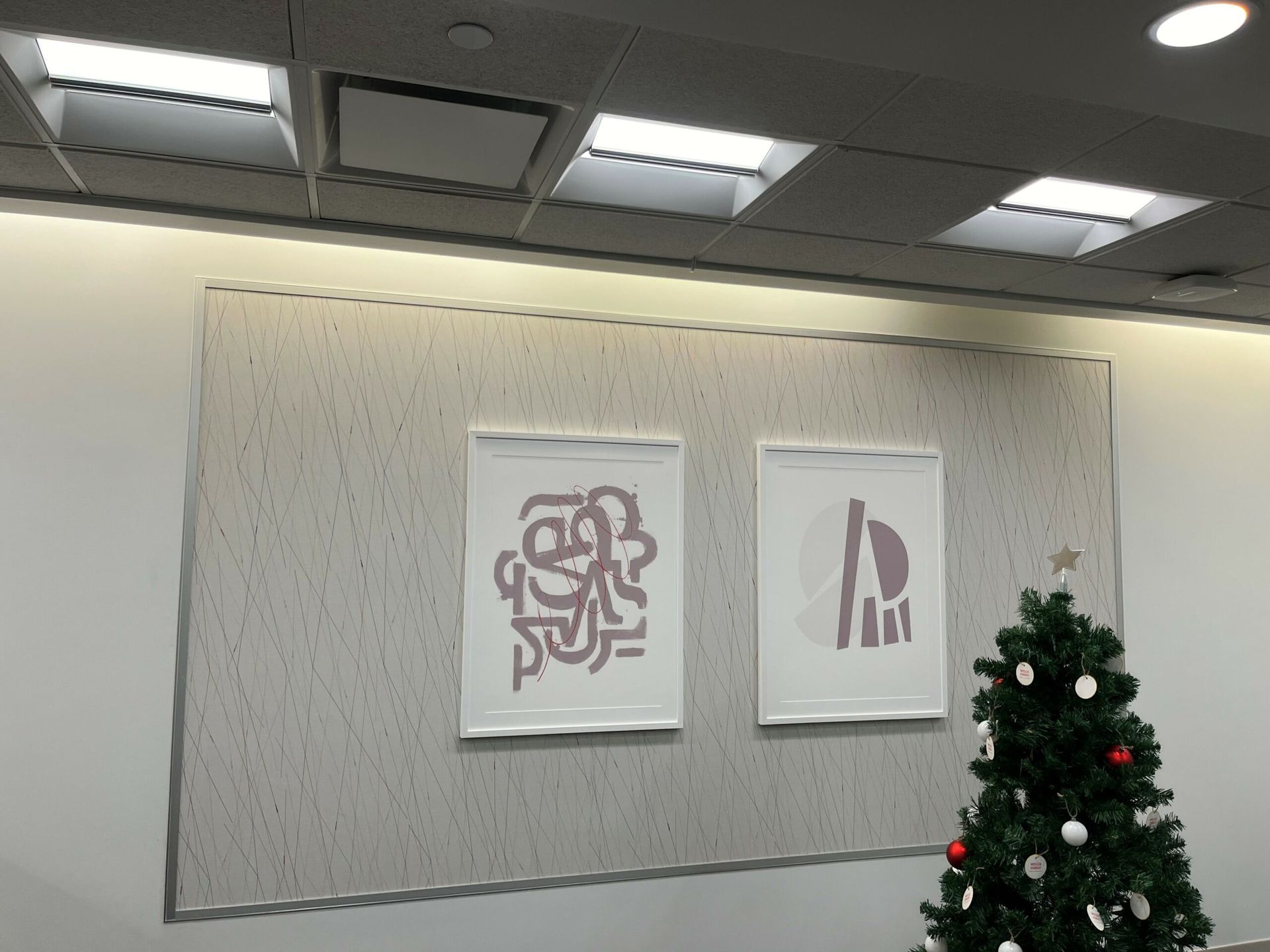 A christmas tree is in front of a wall with two paintings on it