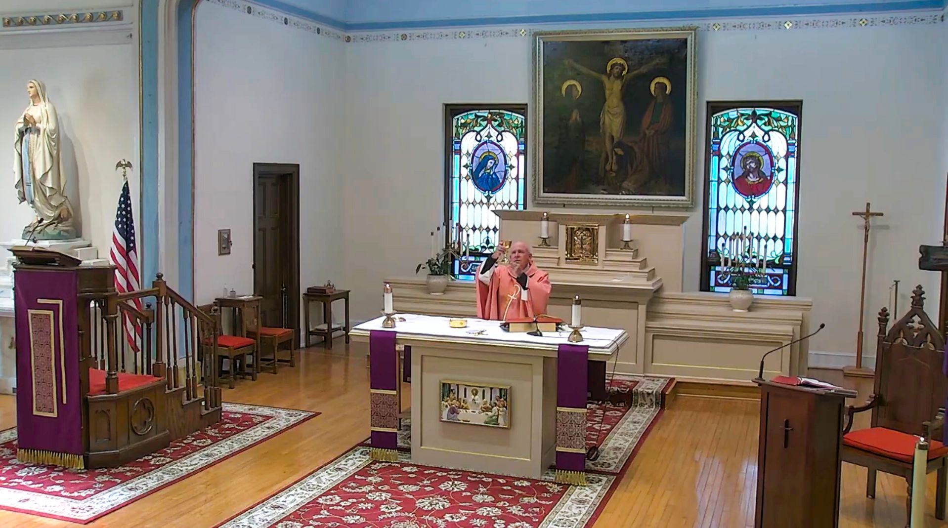 Church sanctuary with altar, stained-glass windows, and a person in pink seated at the center