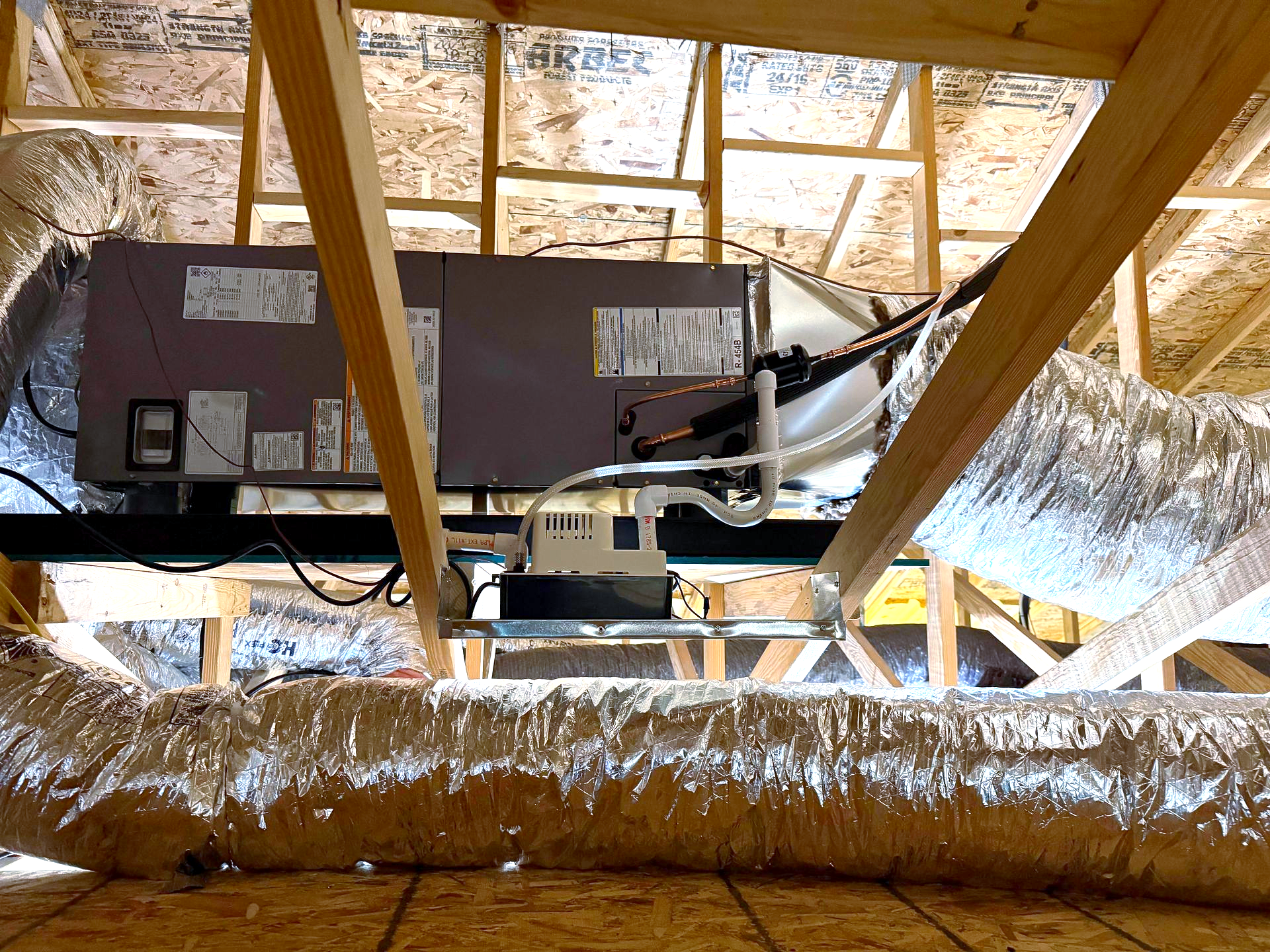 Construction site with metal framing, HVAC ductwork, and an orange lift.