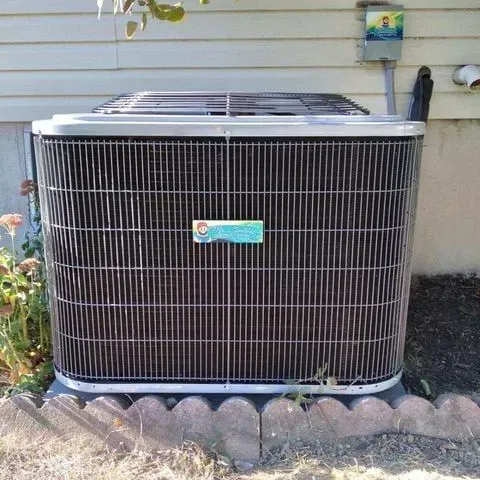 Air conditioning unit outside a house, with a protective metal cage.