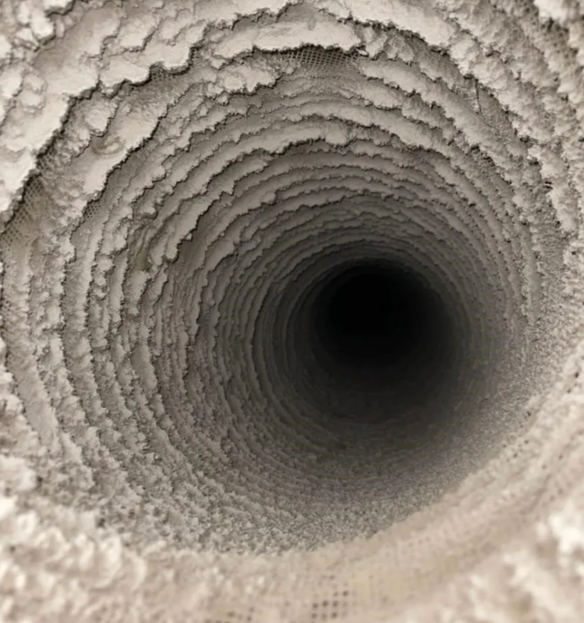 Inside view of a dusty air duct with layers of built-up debris.