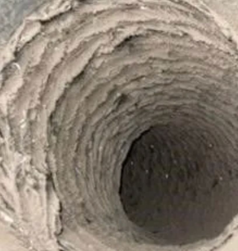 Inside of a dusty, dirty air duct with heavy buildup of debris on the sides.