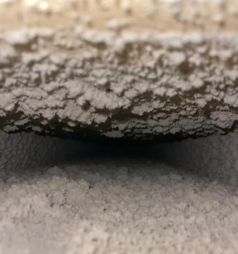Close-up of a surface with a textured, white, crystal-like layer and a dark, shadowed recess.
