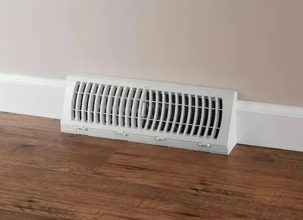 Plumber working under a white sink, using a wrench.