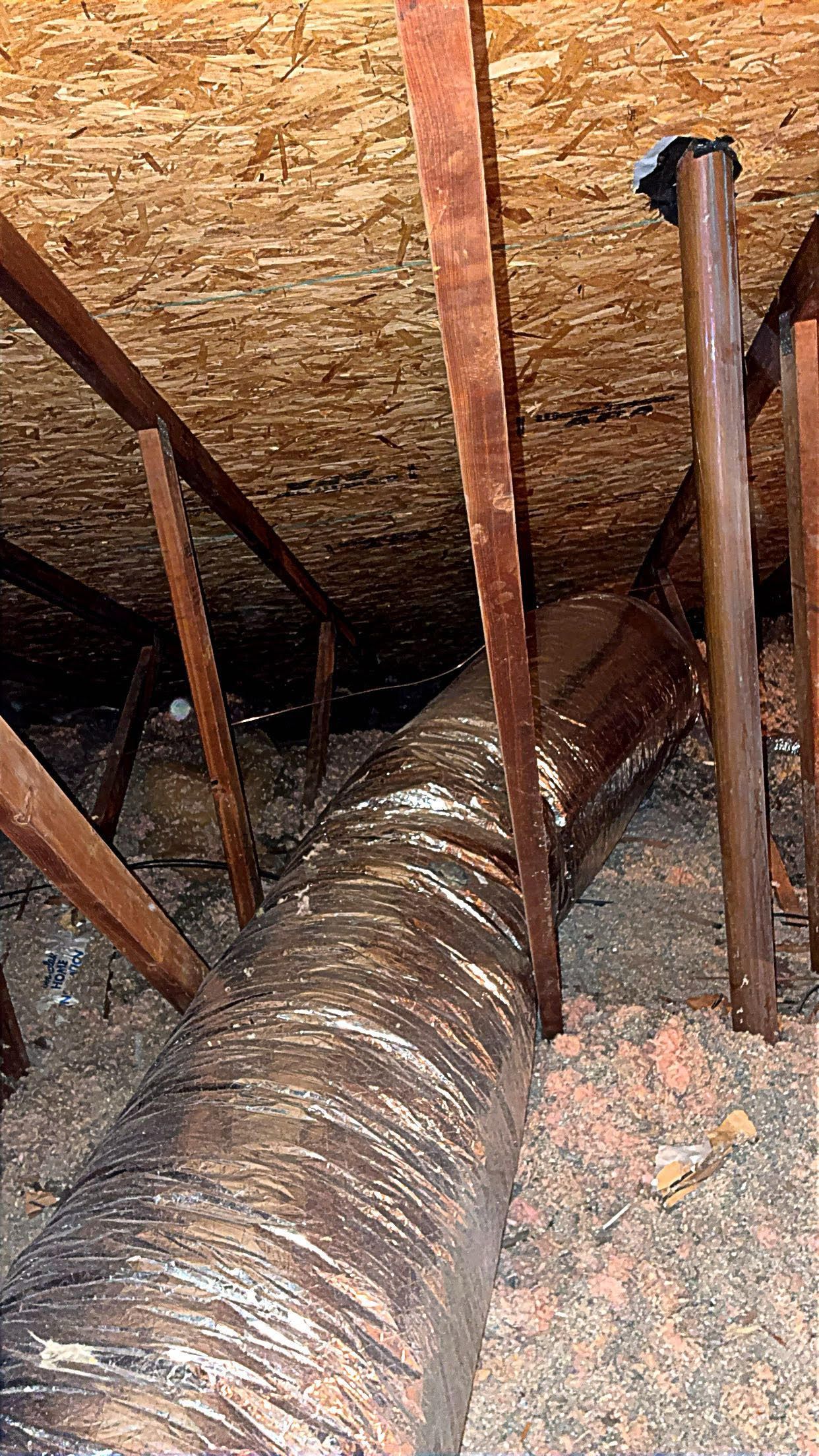 Attic interior with HVAC ducting, wood beams, and insulation.