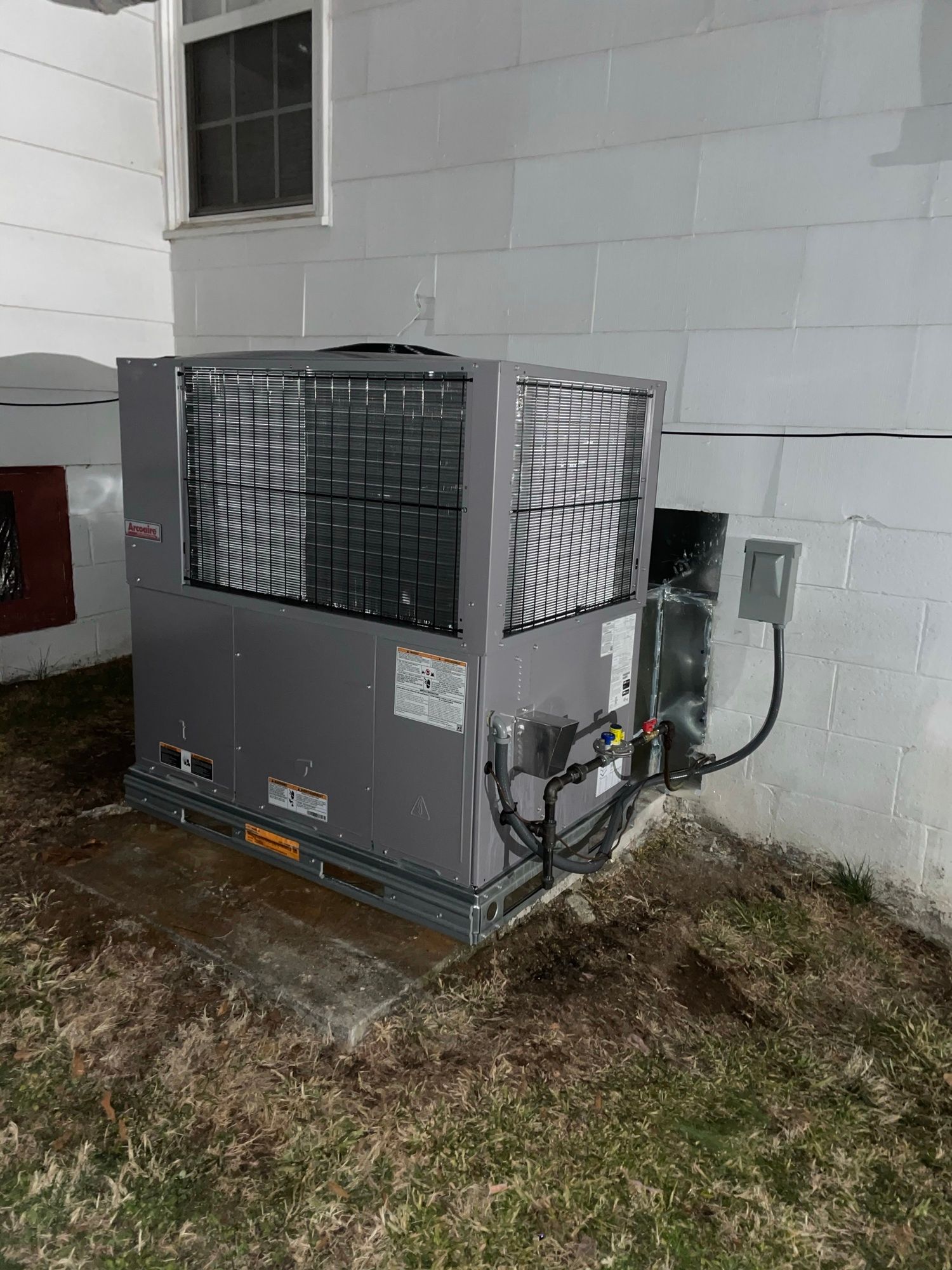 A large air conditioner is sitting in the backyard of a house.