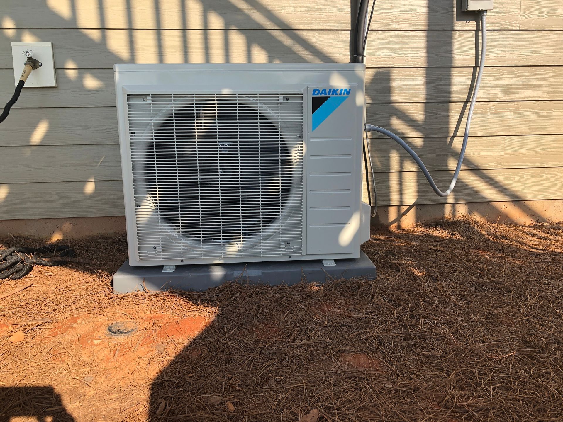 A daikin air conditioner is sitting outside of a house