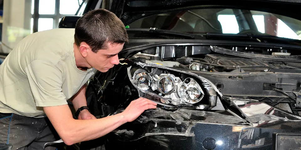 Mechanic inspecting damaged headlight — Waipahu, HI — Westside Fender/Body & Refinishing