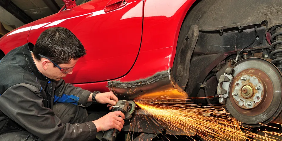 Mechanic doing work on bottom of red car — Waipahu, HI — Westside Fender/Body & Refinishing