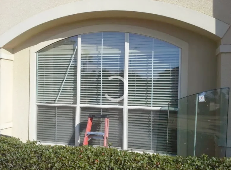 A window with blinds and a ladder in front of it