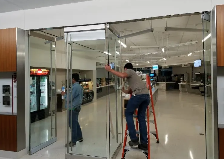 A man standing on a ladder cleaning a glass door