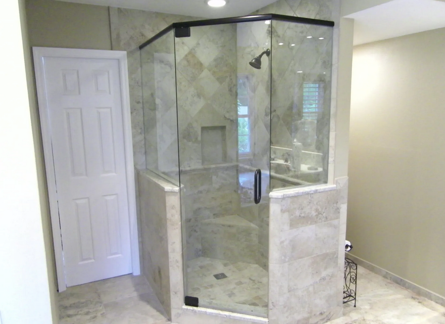 A bathroom with a walk in shower with a glass door.