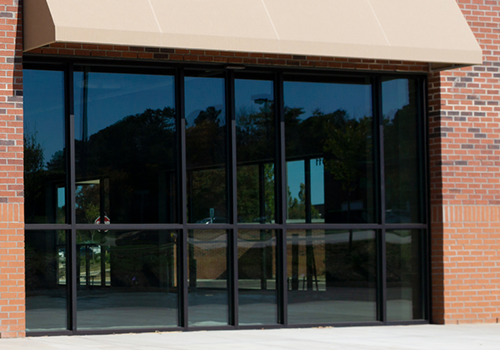 A brick building with a large window and a tan awning.