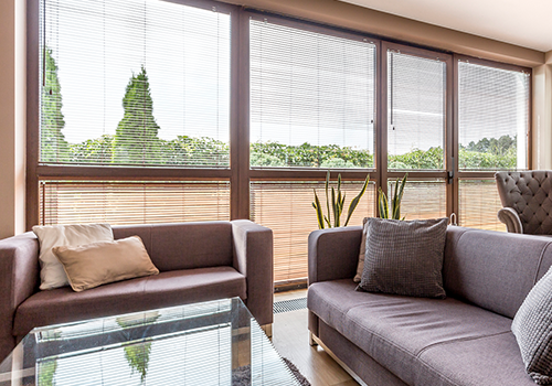 A living room with a couch , chair , coffee table and lots of windows.