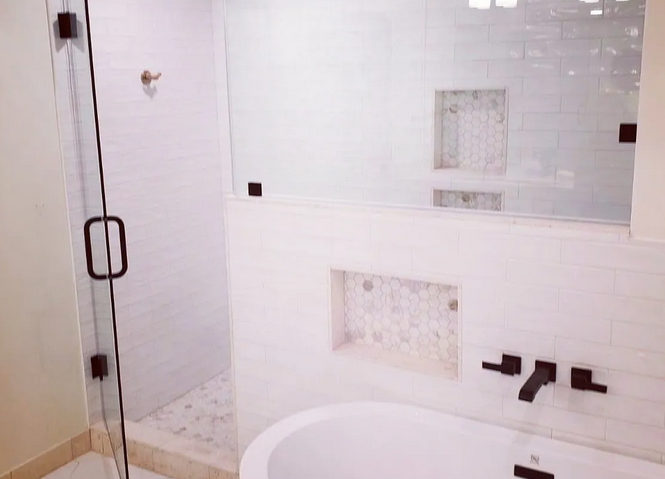 A bathroom with a tub , shower , and glass door.